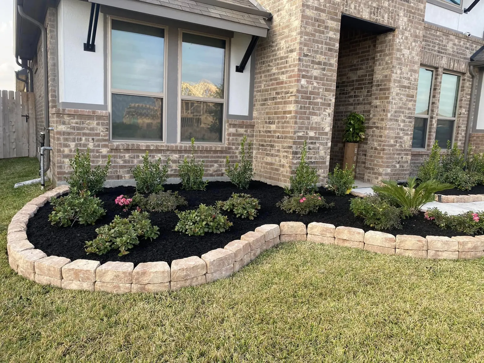 Finished residential planting bed with flowers, mulch, and stone edging