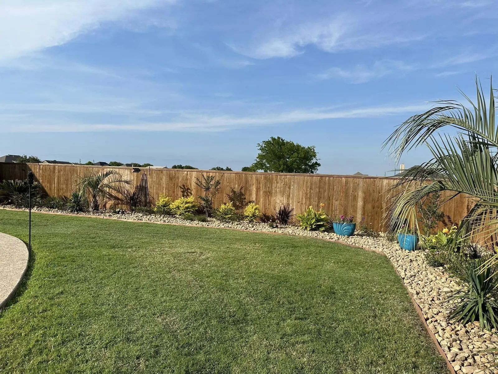 Wide view of a completed backyard landscape and rock border