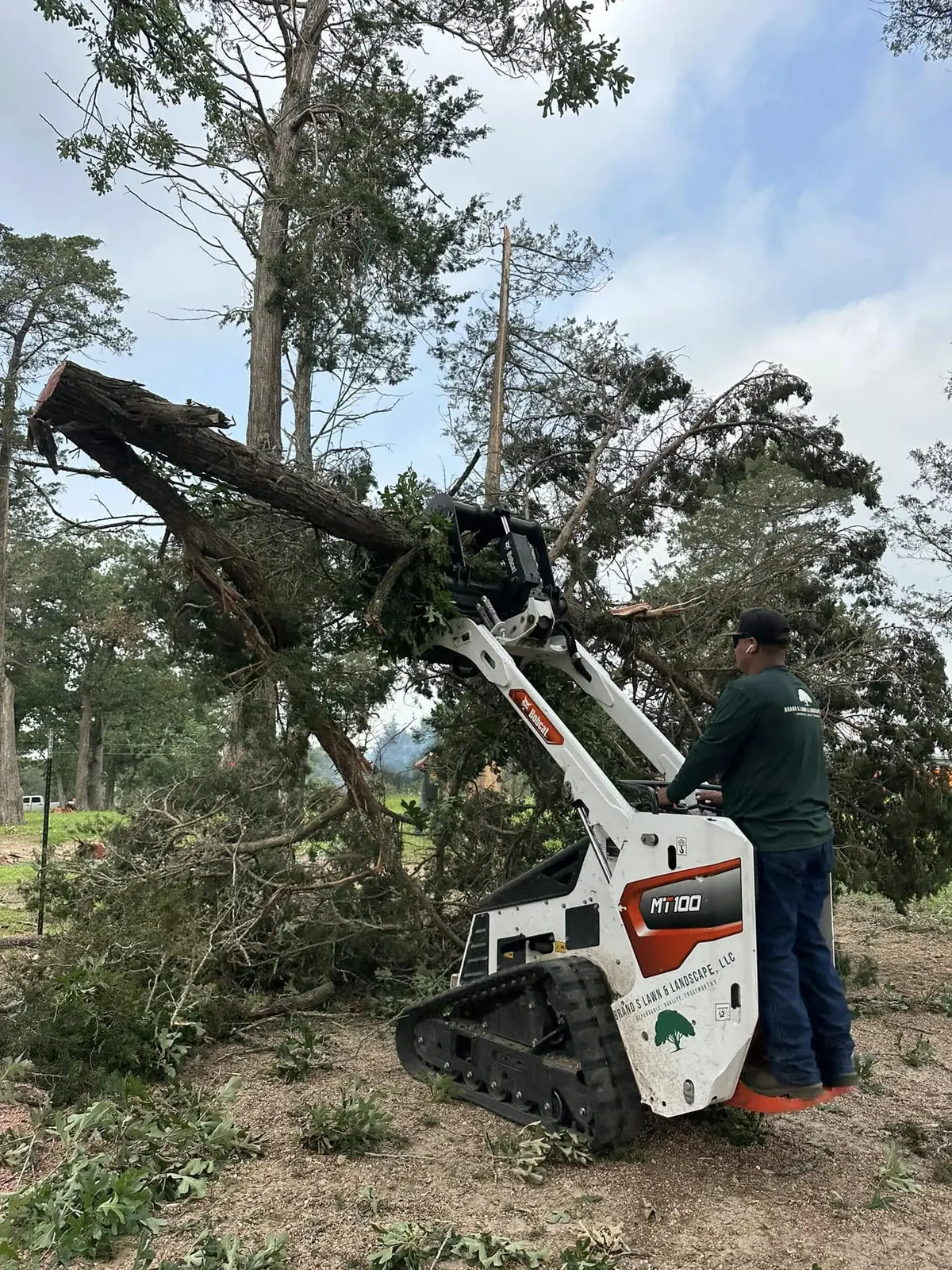 Skid-steer handling broken limbs during debris cleanup