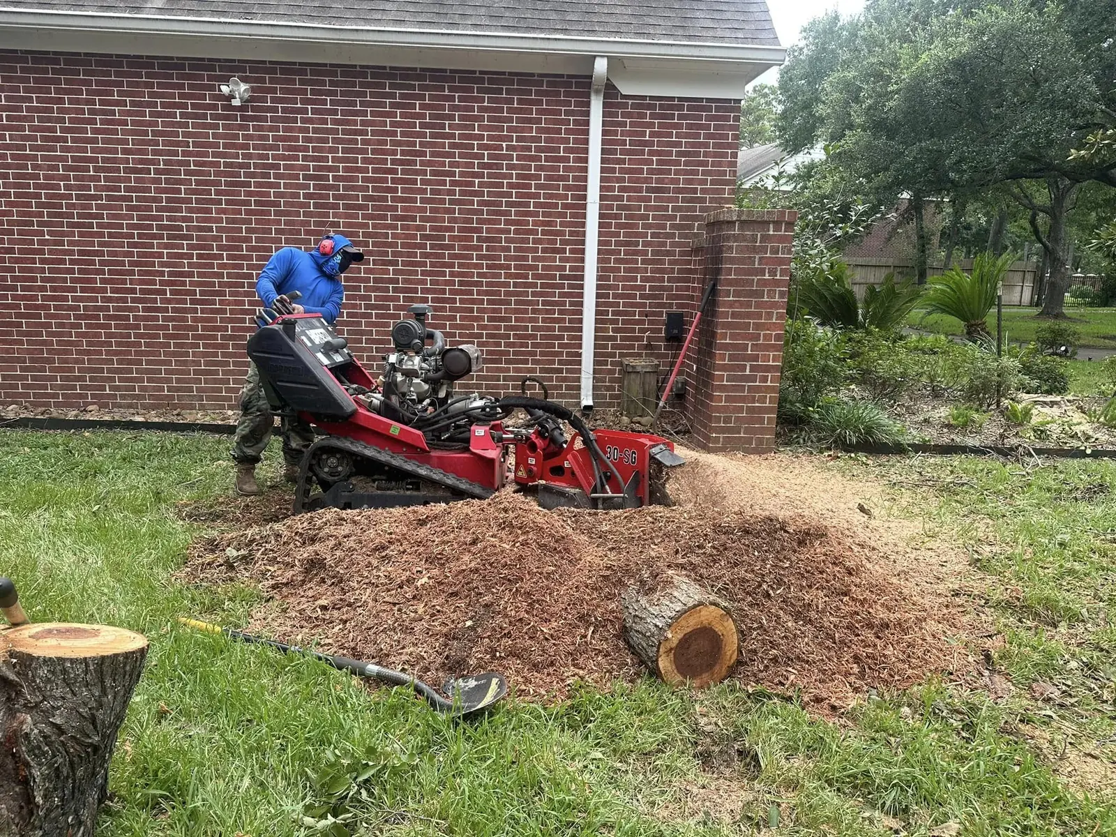 Stump grinder operating beside a brick home