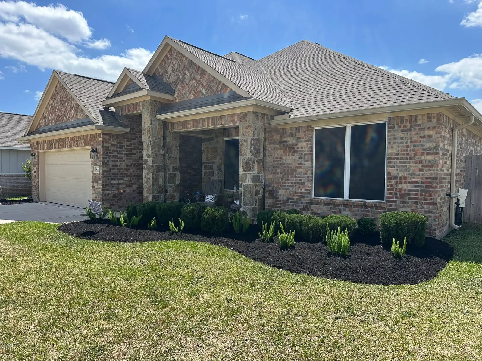 Completed curved residential mulch bed and foundation planting